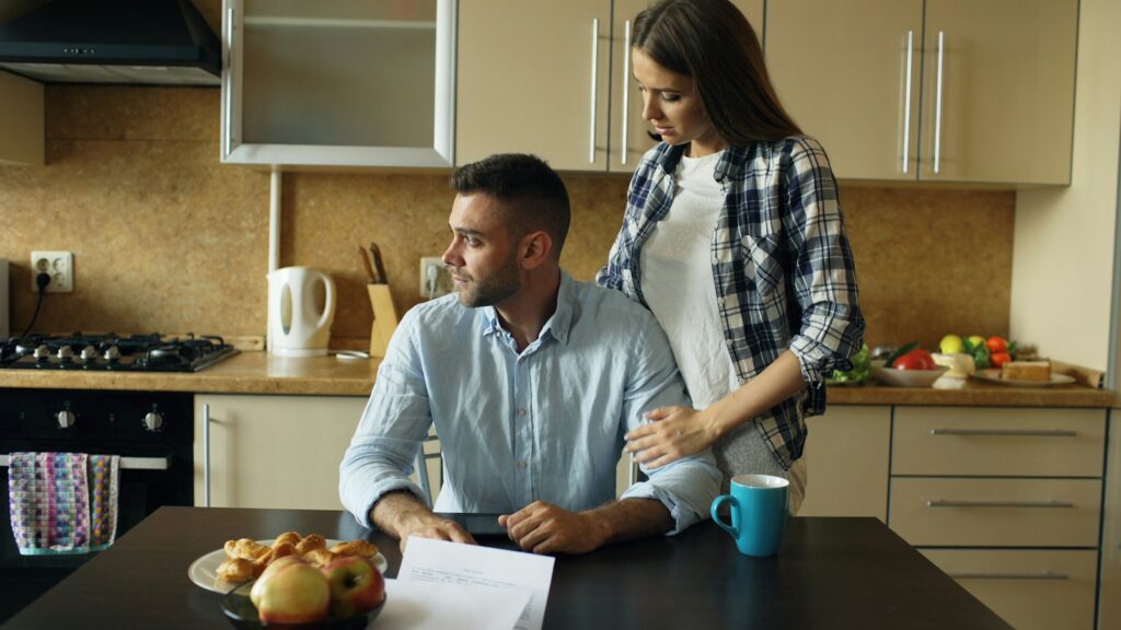 זוג יושב ליד שולחן המטבח ובוחן מסמכים לבניית תמהיל משכנתא
